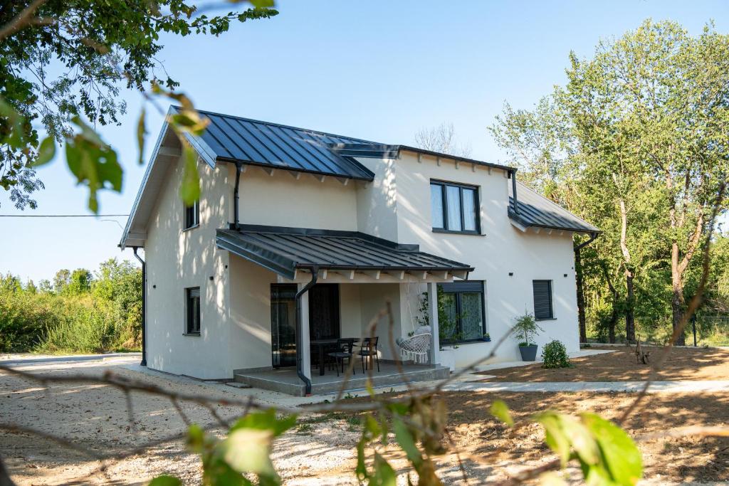 a white house with a metal roof at Holiday Home Ari in Lički Ribnik