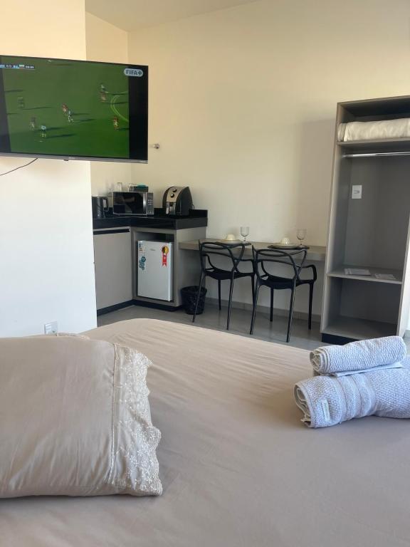 a room with a bed with a tv on the wall at Alphaville Studios in Pirapora