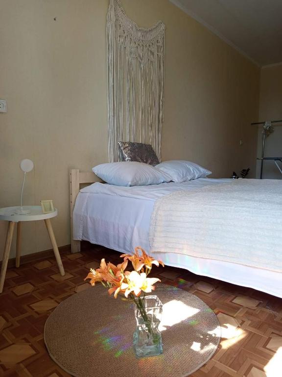 a bedroom with a bed and a table with a vase with flowers at Квартира над Парусом in Zhmerynka
