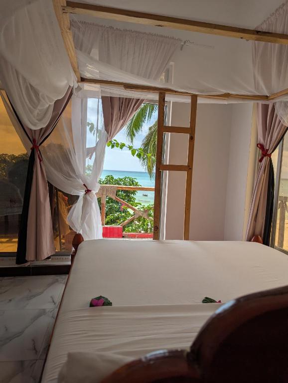 a bedroom with a bed with a view of the ocean at Nisandra Beach Hotel in Nungwi