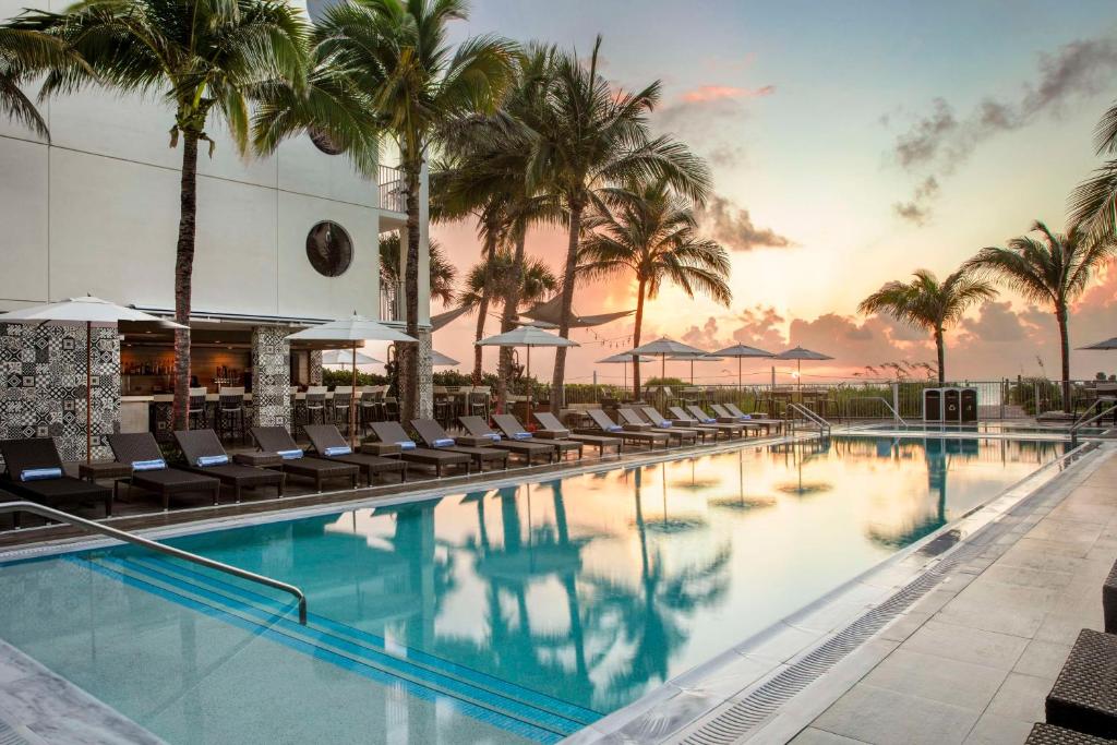 a swimming pool with chairs and palm trees at Costa d'Este Beach Resort & Spa in Vero Beach