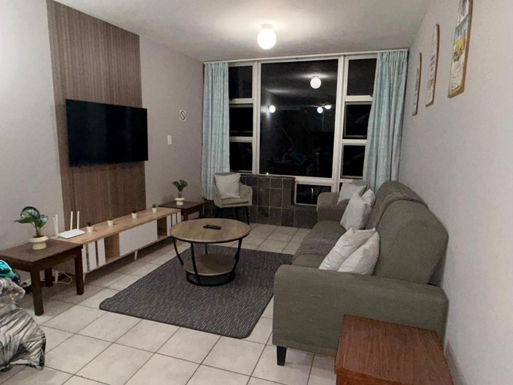 ein Wohnzimmer mit Sofa, Tisch und Fernseher in der Unterkunft Ocean rest in Scottburgh
