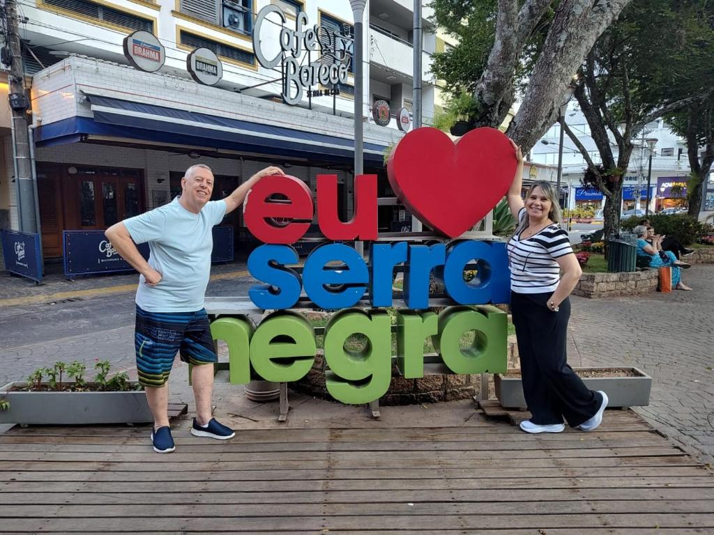 a man and a woman standing next to a sign at Serra Negra Piemonte Flat Paz e Lazer Num Só Lugar in Serra Negra