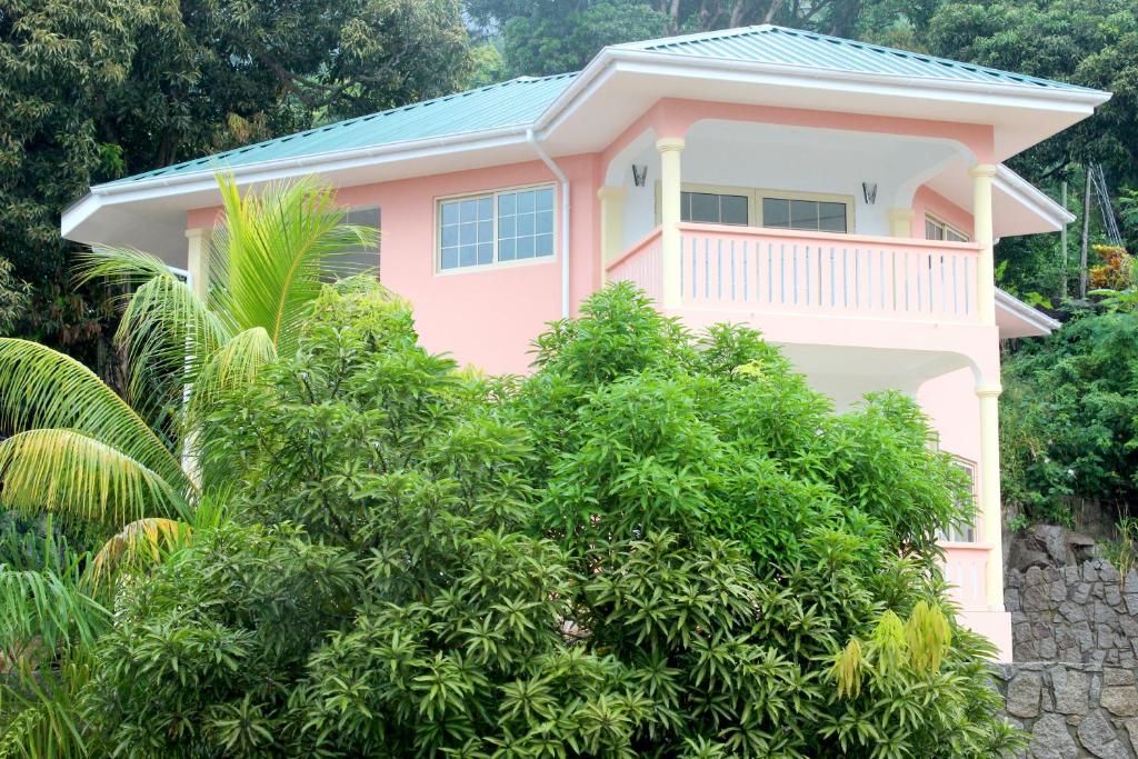 a pink house with trees in front of it at Korrine's Cottage HORIZON in Beau Vallon