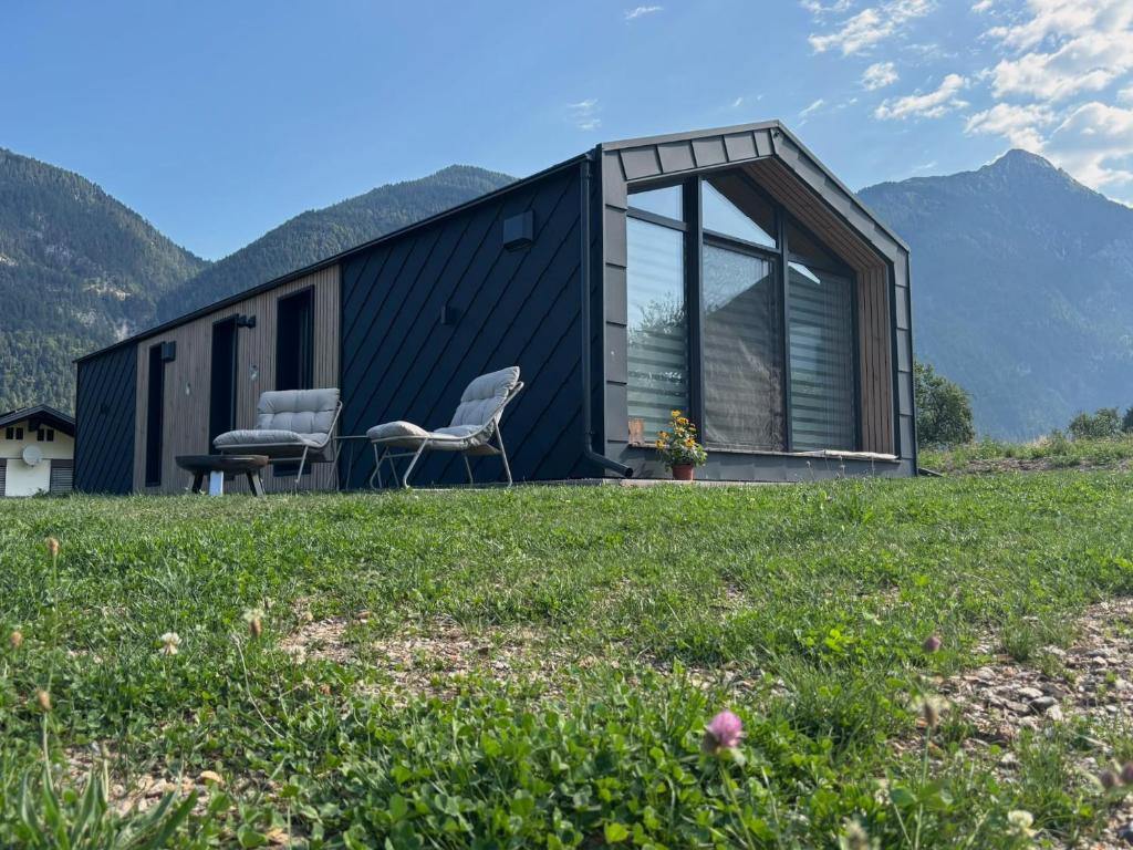 a black house with two chairs in a field at Häuschen am Traunig in Hermagor