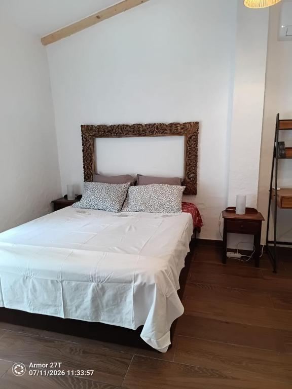 a bedroom with a bed with white sheets and pillows at Casa do Adro in Corte do Gafo de Cima