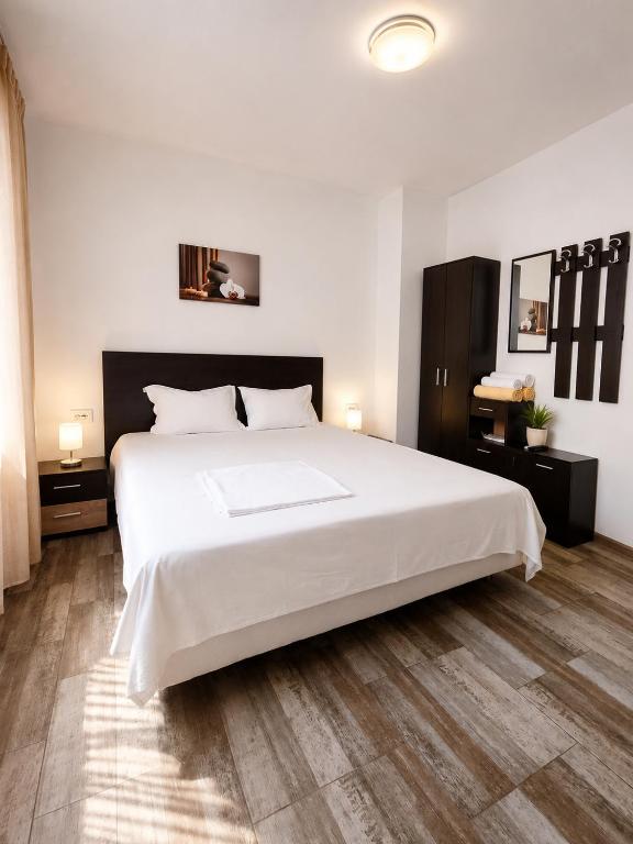 a bedroom with a large white bed and wooden floors at Alex City Apartment Gabrovo in Gabrovo