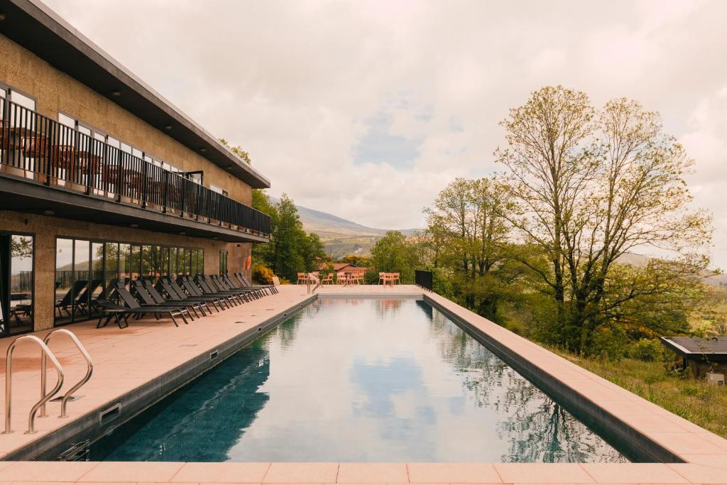 a swimming pool in front of a building at Estrela Serenity - Mountain Resort in Folgosinho