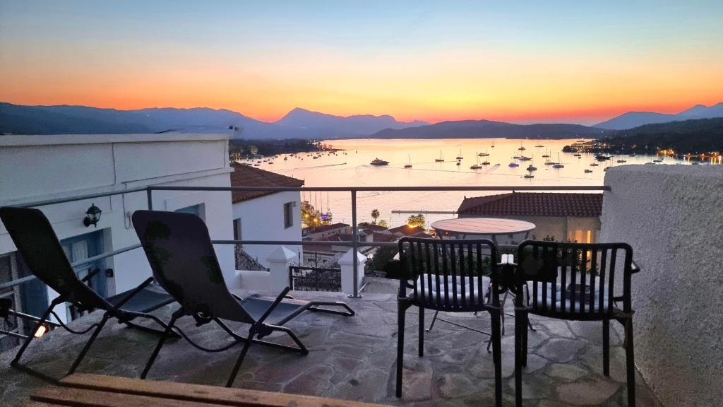 a balcony with chairs and a table and a view of a harbor at Panoramic View apartment in Poros