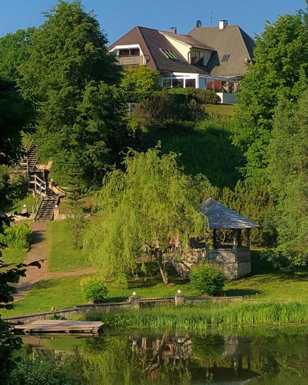 a house next to a lake with a gazebo at Jaunkrastmaļi in Kandava