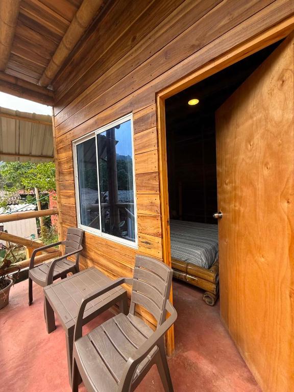 a porch with two chairs and a bed and a window at Greengoat Haven in Santa Marta