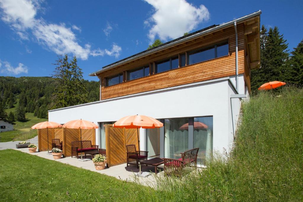 a house with patio furniture and umbrellas at Bed and Breakfast Raschainas Lenzerheide in Sporz