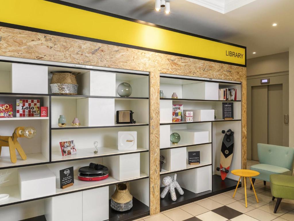 a library with white shelves and a yellow wall at Aparthotel Adagio Access Paris Vanves - Porte de Versailles in Vanves