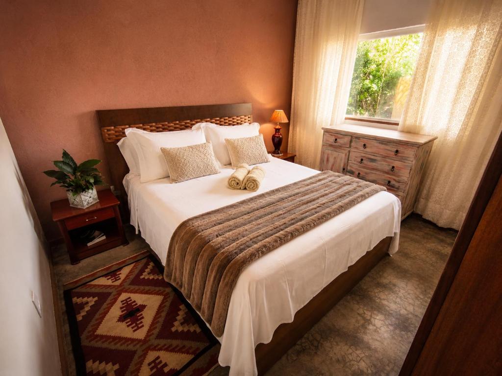 a bedroom with a large bed and a window at Villa Pella - Chalé Tulipa- com café manhã in Brumadinho