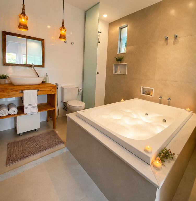 a large bathroom with a large tub and a toilet at Villa Pella - Chalé Rosa- hidro e café manhã in Brumadinho