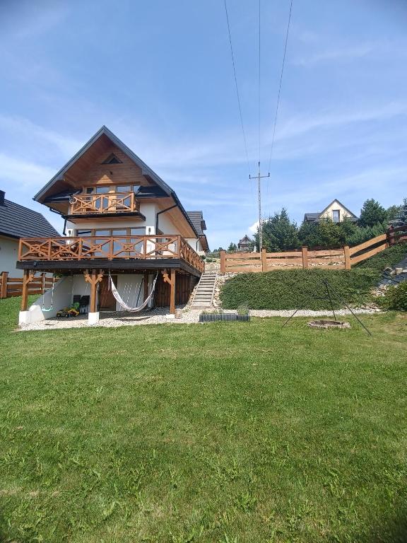 a house with a deck and a grass yard at Hubacówka in Huba