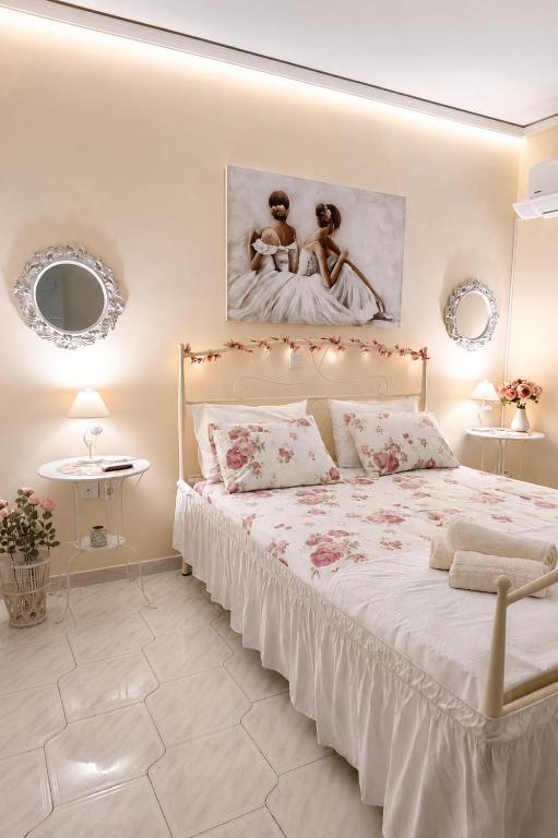 a white bedroom with a bed with a painting on the wall at Erofili's Apartment ONLY 700 meters from the beach in Ialysos