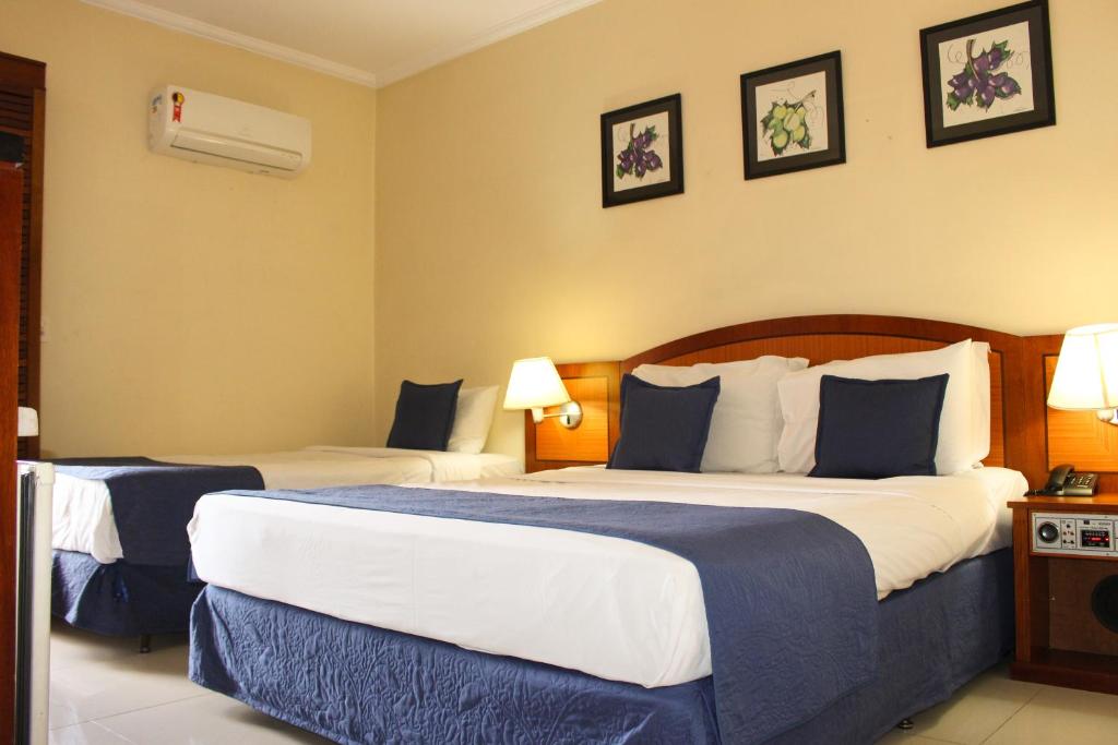 a hotel room with two beds with blue and white sheets at Summit Suites Jundiai in Jundiaí