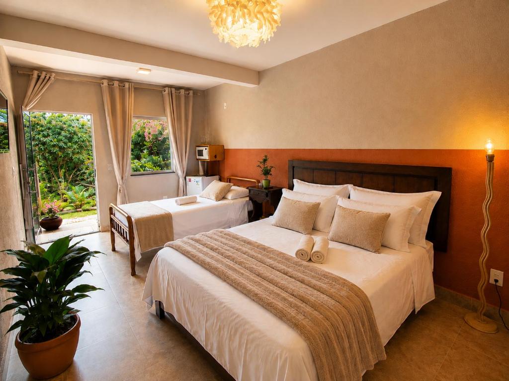 a hotel room with two beds and a large window at Villa Pella - Chalé Cravo- café da manhã in Brumadinho