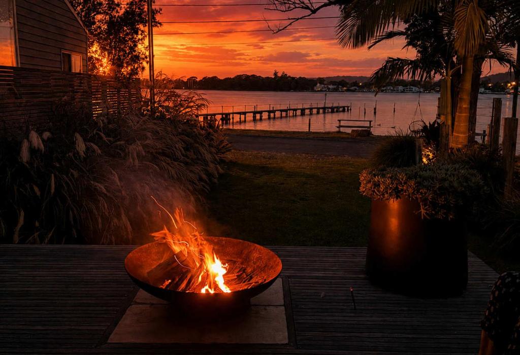 a fire pit on a table with a sunset in the background at Phegans Bay Waterfront Haven in Blackwall