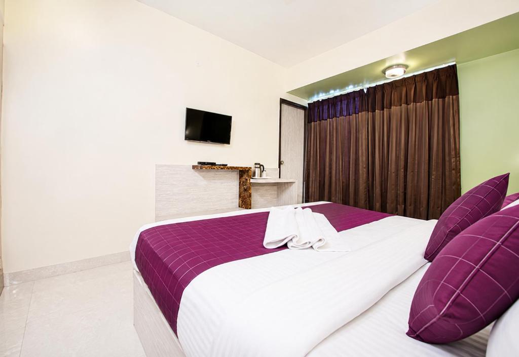 a bedroom with a large bed with purple pillows at Hotel Hotel HVH Elite Kashi Vishwanath # Resturent and Free Wifi in Varanasi