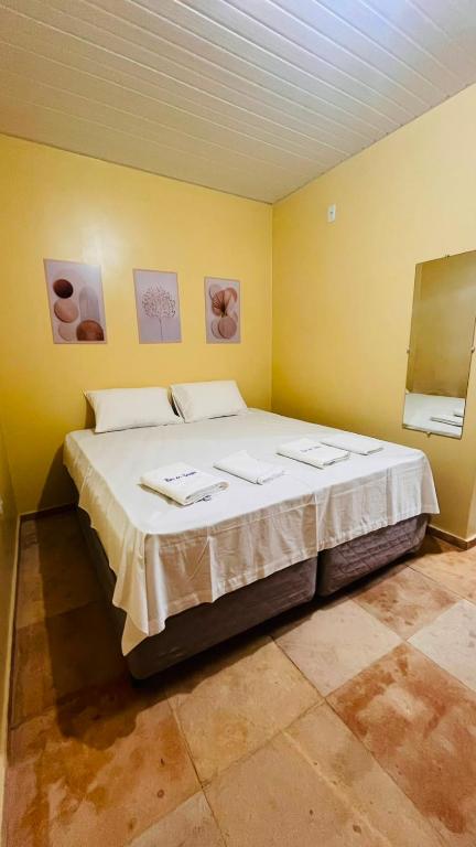a bedroom with a large bed in a yellow wall at Mini Suítes - Centro de Tutóia in Tutóia