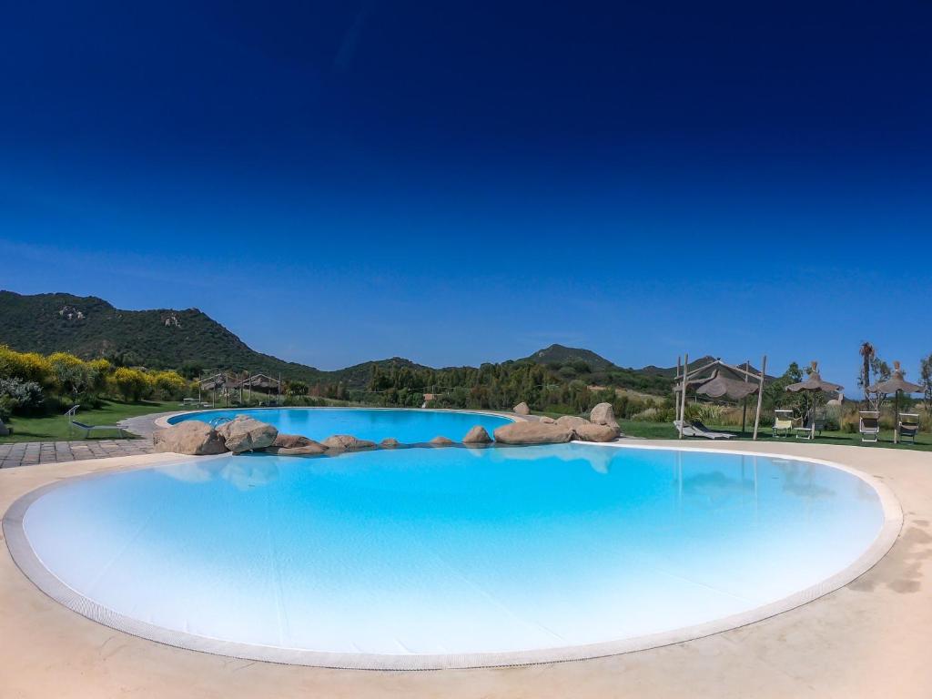 a large swimming pool with blue water at Li Conchi 13 in Castiadas