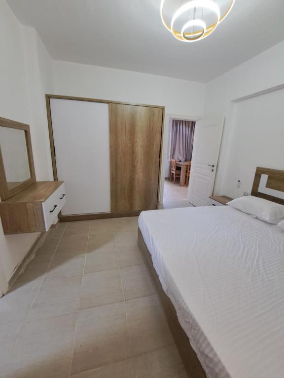 a bedroom with a white bed and a mirror at Adel Apartments at alkarma resorts& aquapark in Hurghada