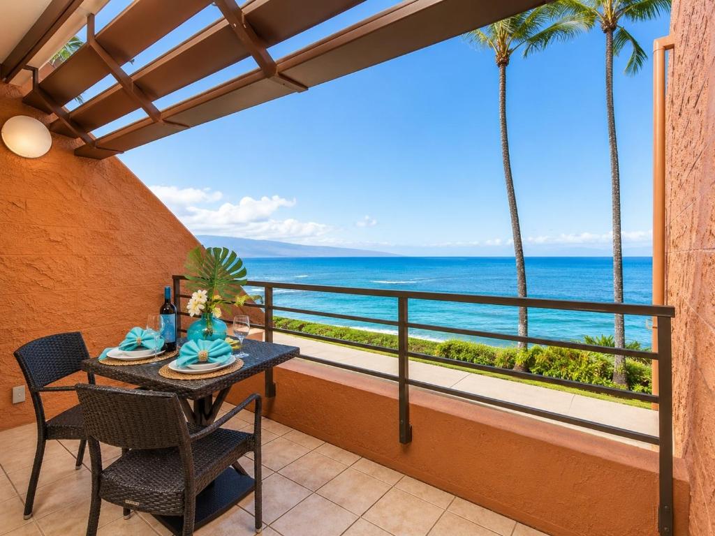 a balcony with a table and chairs and a view of the ocean at Kuleana 613 1 Bdrm condo in Kahana