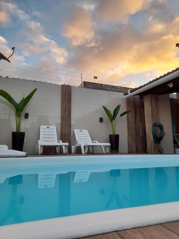 a view of a swimming pool with chairs and a house at Casa Vilarejo in Arembepe