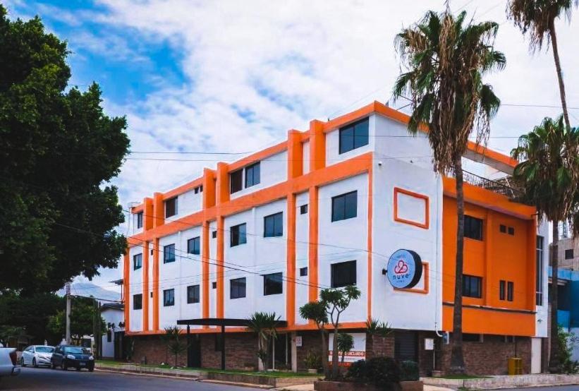 ein orange-weißes Gebäude mit einer Palme in der Unterkunft Nuve Express Abasolo in Torreón