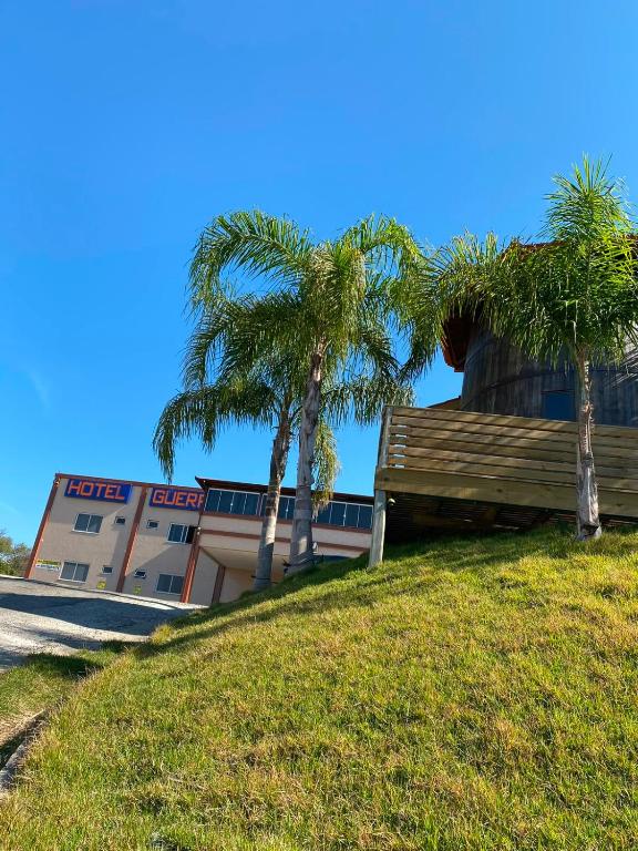 two palm trees in front of a building at Hotel Guerra - Pousada Montebelo in Jaguaruna
