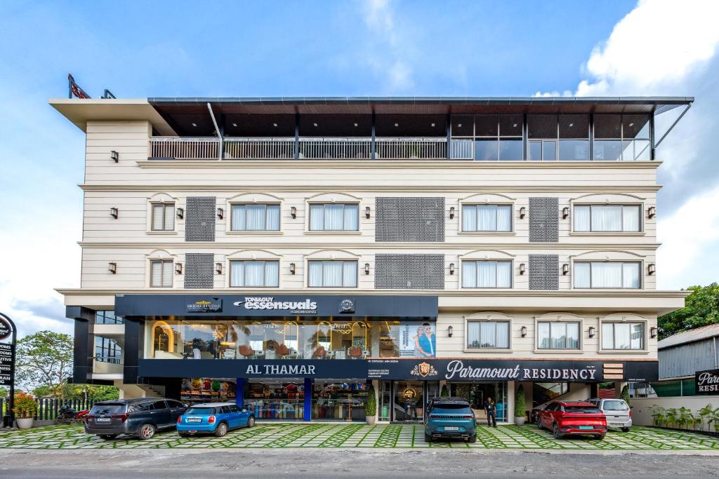 a large white building with cars parked in front of it at Paramount Residency in Nedumbassery