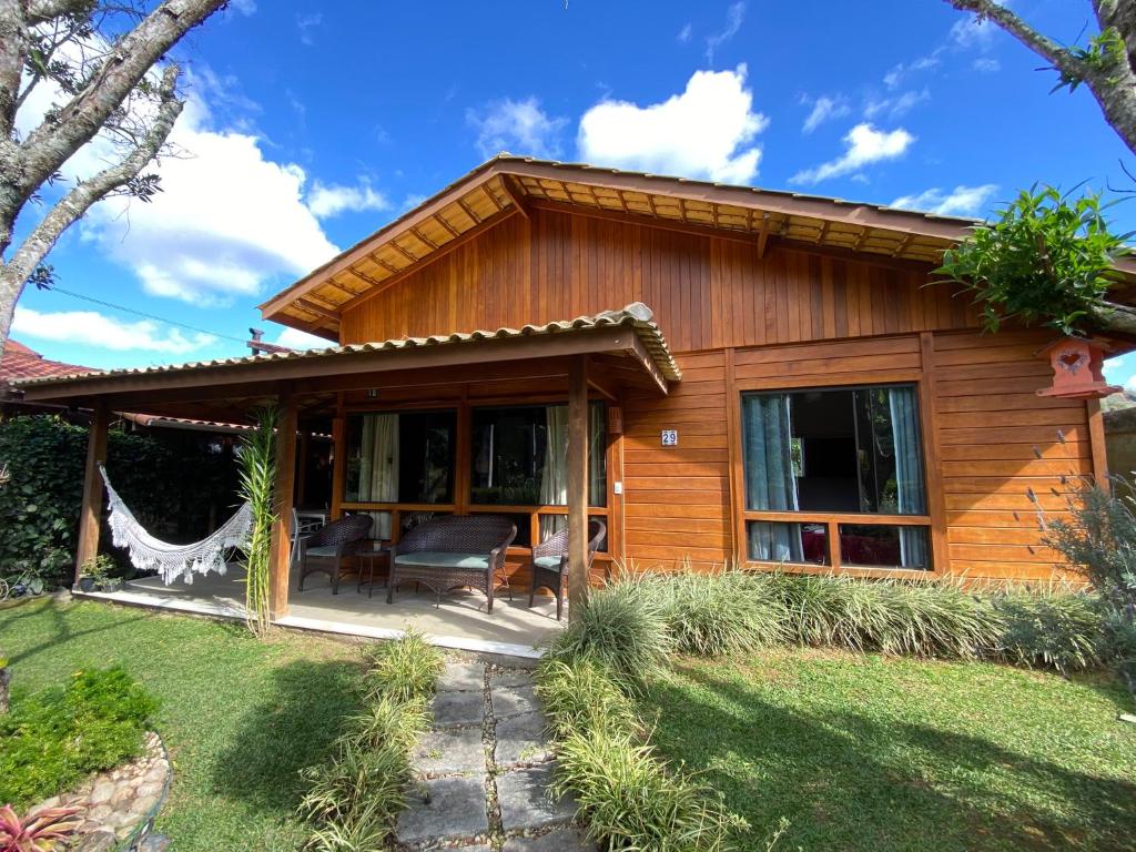 a wooden house with a patio and a yard at Paz e Conforto na Serra Pet Friendly in Teresópolis
