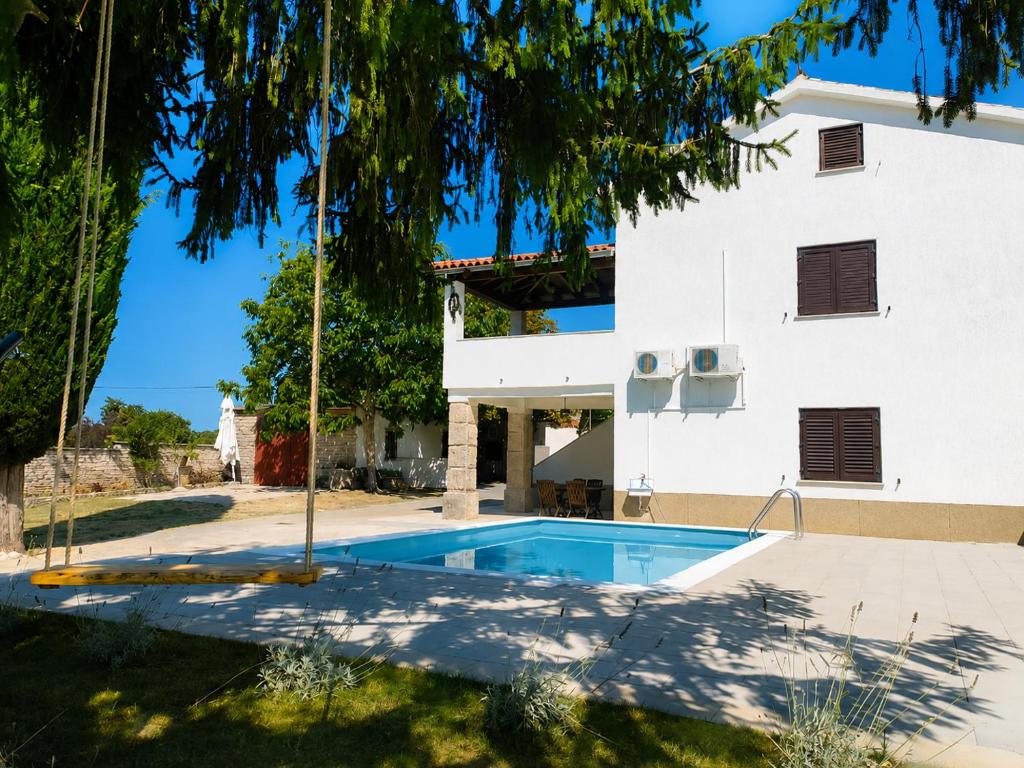 a villa with a swimming pool in front of a building at Hiža Bili in Svetvinčenat