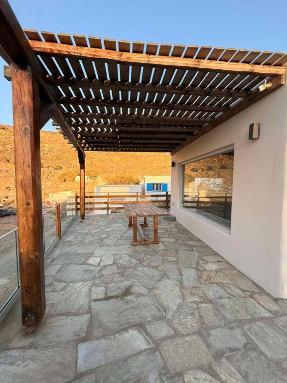 a patio with a wooden bench and a wooden pergola at mare Mali Tinos in Mamádhos