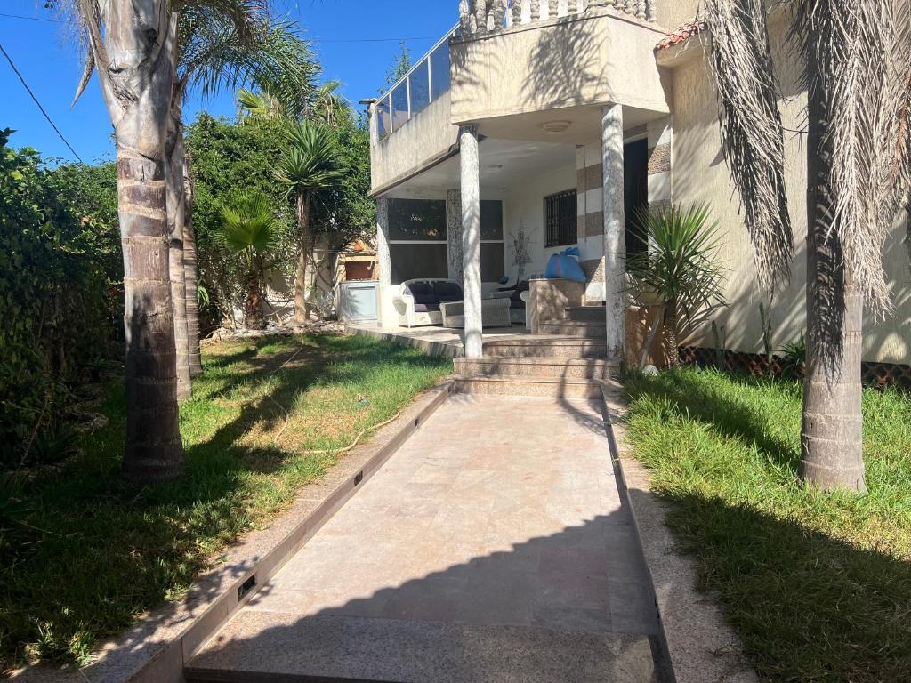 a house with a palm tree in front of it at Villa Tamaris, Dar Bouazza in Tamaris