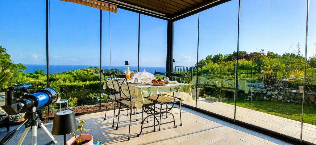 a large glass room with a table and a view of the ocean at Azores Panorama Lodge in Norte Pequeno
