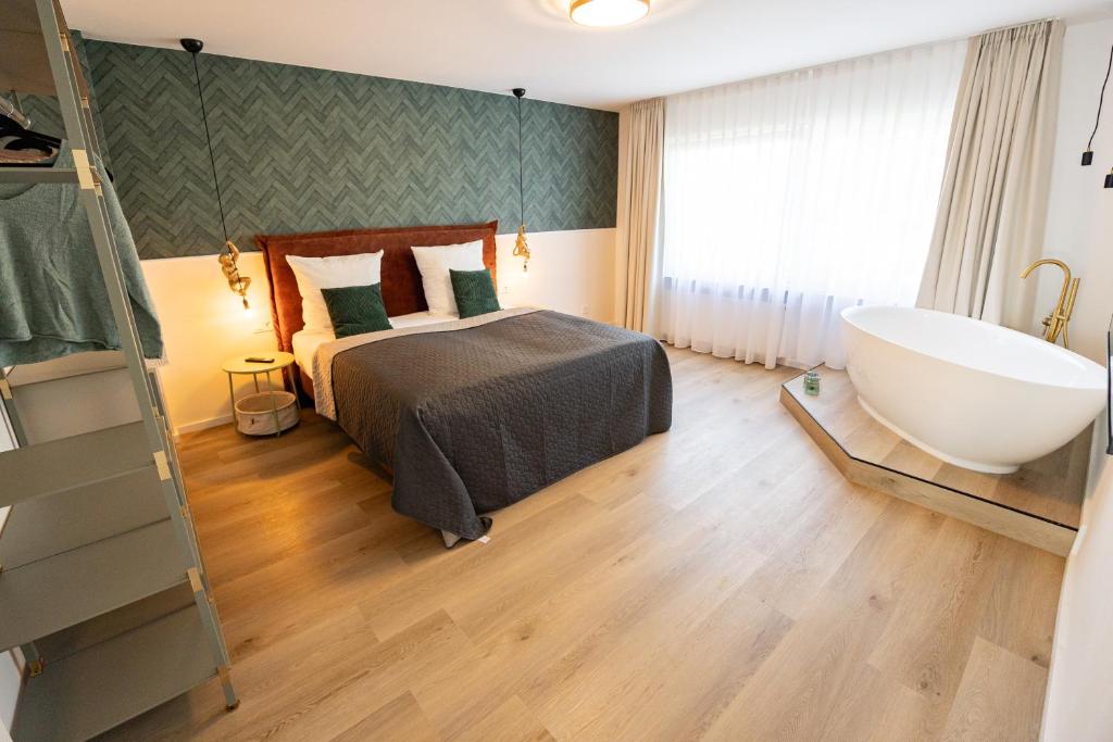 a bedroom with a bed and a bath tub next to a window at ME LIVING Villa am Kurpark - Design Apartments in Bad Salzuflen