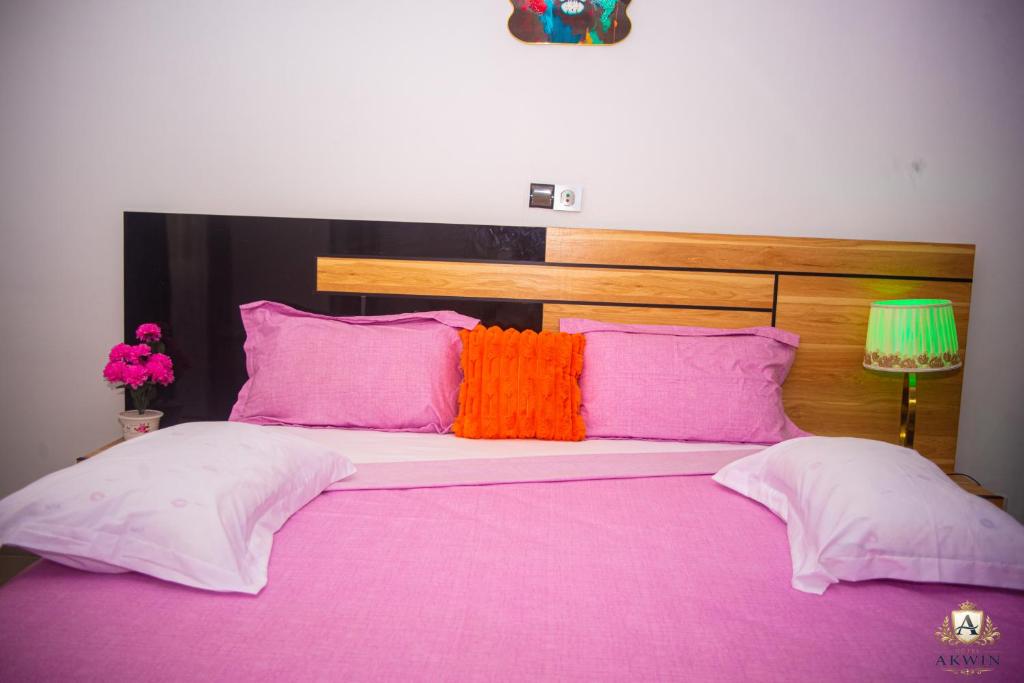 a bed with pink and orange pillows on it at Hôtel Akwin Kpalimé in Palimé