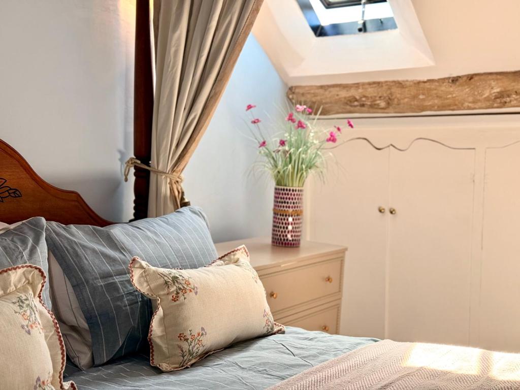 a bedroom with a bed with a vase of flowers at Wind in the Willows Moreton in Marsh in Moreton in Marsh