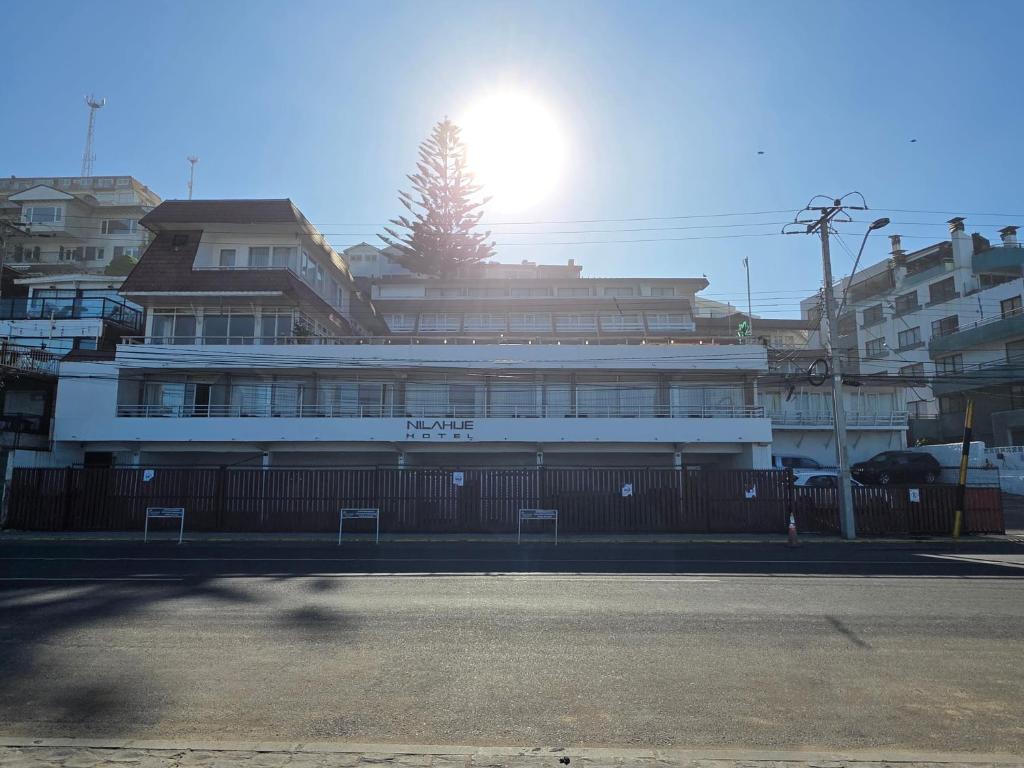 a large white building with the sun in the background at Hotel Nilahue in Viña del Mar