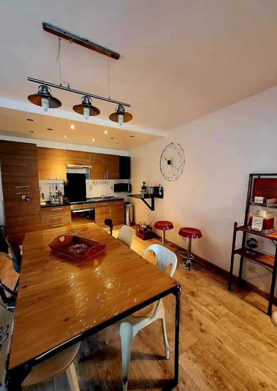 a dining room with a wooden table and a kitchen at La Ch'tite Maison in Masnières