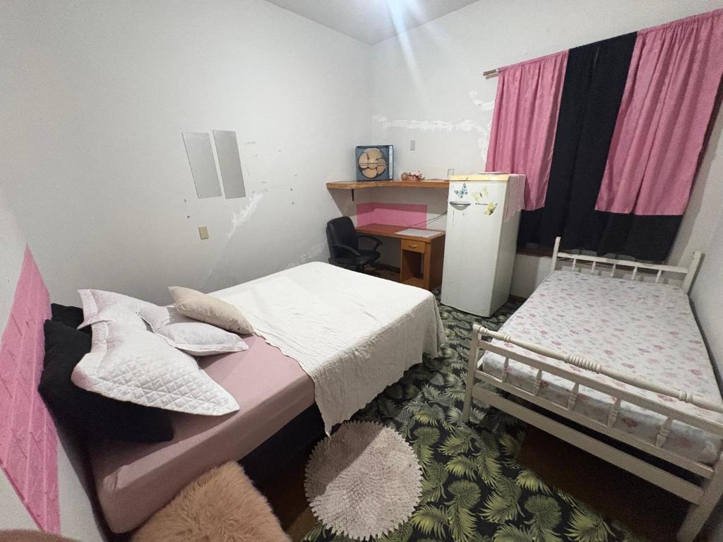a bedroom with two beds and a refrigerator at POUSADA OCZ Centro1 in Osvaldo Cruz