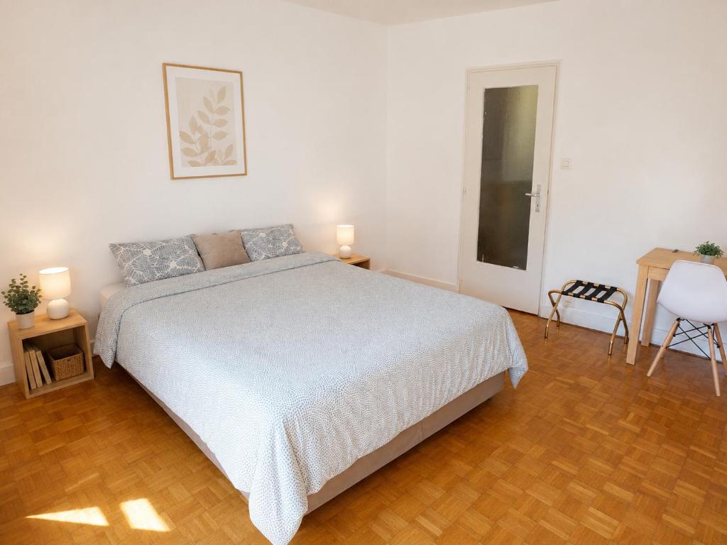 a bedroom with a bed and a table and a chair at Chambre Lac Rose in Lausanne
