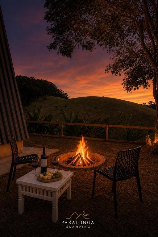 a fire pit with a table and two chairs and a table with a fire pit at Paraitinga Glamping in São Luiz do Paraitinga