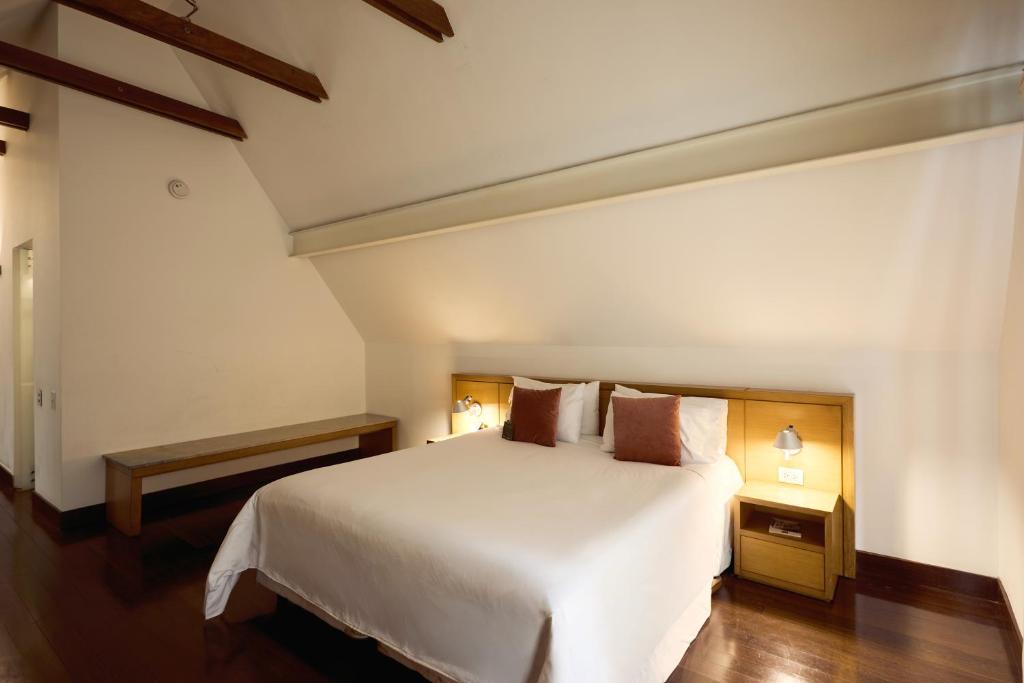 a bedroom with a white bed and a wooden floor at Hotel bh La Quinta in Bogotá