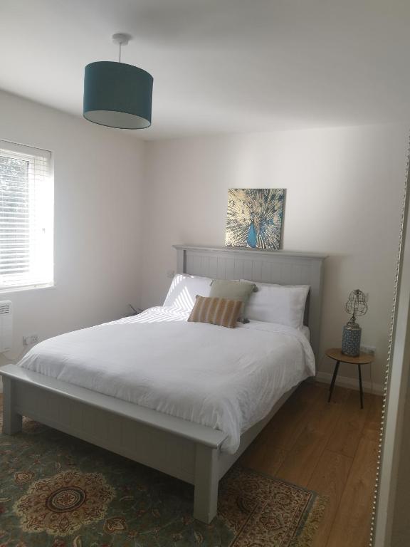 a bedroom with a large bed with white sheets at knightstown Haven in Valentia Island
