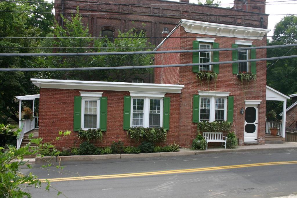 a red brick house with green shutters and a bench at Riverview Organic Bed & Breakfast and Wellness Center in Piermont