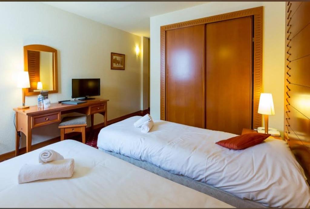 a hotel room with two beds and a desk at Belambra terra nova in La Plagne Tarentaise